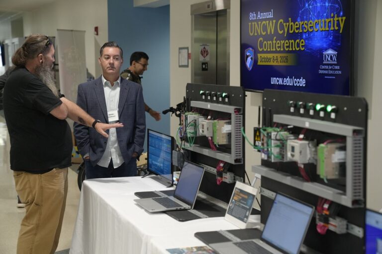 Attendees engage with cybersecurity demonstration equipment at the 8th Annual UNCW Cybersecurity Conference.